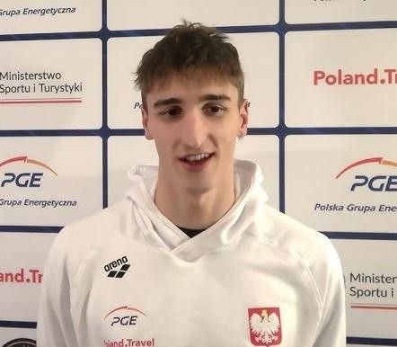 Portret Ksawerego Masiuka, polskiego pływaka, uśmiechniętego i pewnego siebie, z medalem lub w stroju sportowym.