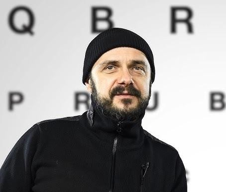 Arkadiusz Jakubik, wokalista zespołu Dr Misio, na scenie podczas koncertu, śpiewający do mikrofonu.