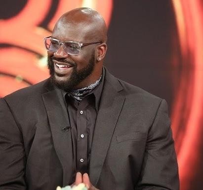 Shaquille O'Neal w zabawnej pozie, symbolizującej jego karierę aktorską i muzyczną, ukazujący jego humor i wszechstronność.