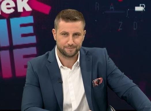 Miłosz Kłeczek podczas intensywnego wywiadu z politykiem w studiu telewizyjnym.