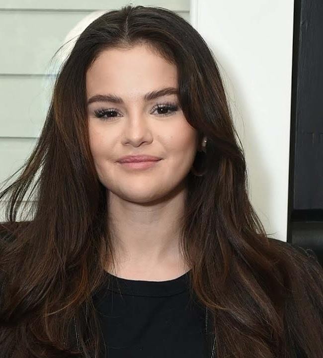 Selena Gomez uśmiechnięta, trzymająca telefon, symbolizująca jej zaangażowanie w media społecznościowe i promowanie zdrowia psychicznego na Instagramie.